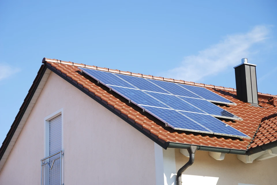 Deux professionnels sur un toit analysent des données sur tablette numérique près d'une installation de panneaux solaires photovoltaïques
